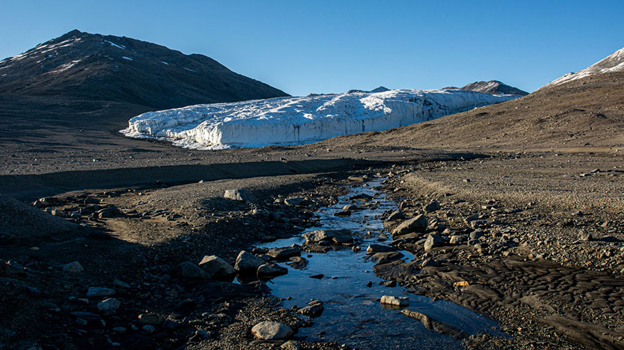 Water flowing from melting glaciers flows over the sandy soils of the McMurdo Dry Valleys, collecting iron particles before flowing into the nearby sea. 