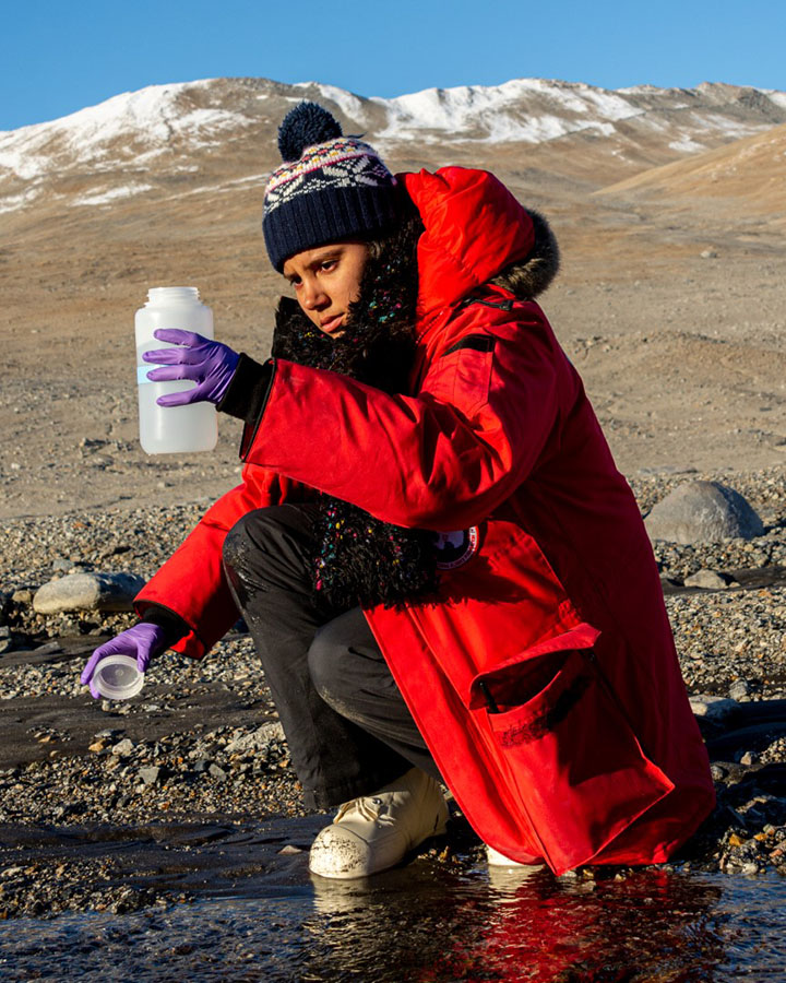 In the Miers Valley, Melisa Diaz collects a water sample from a stream of glacial runoff. 