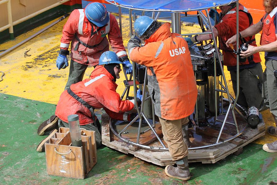 Scientists and marine technicians work to remove samples of mud from the Megacorer