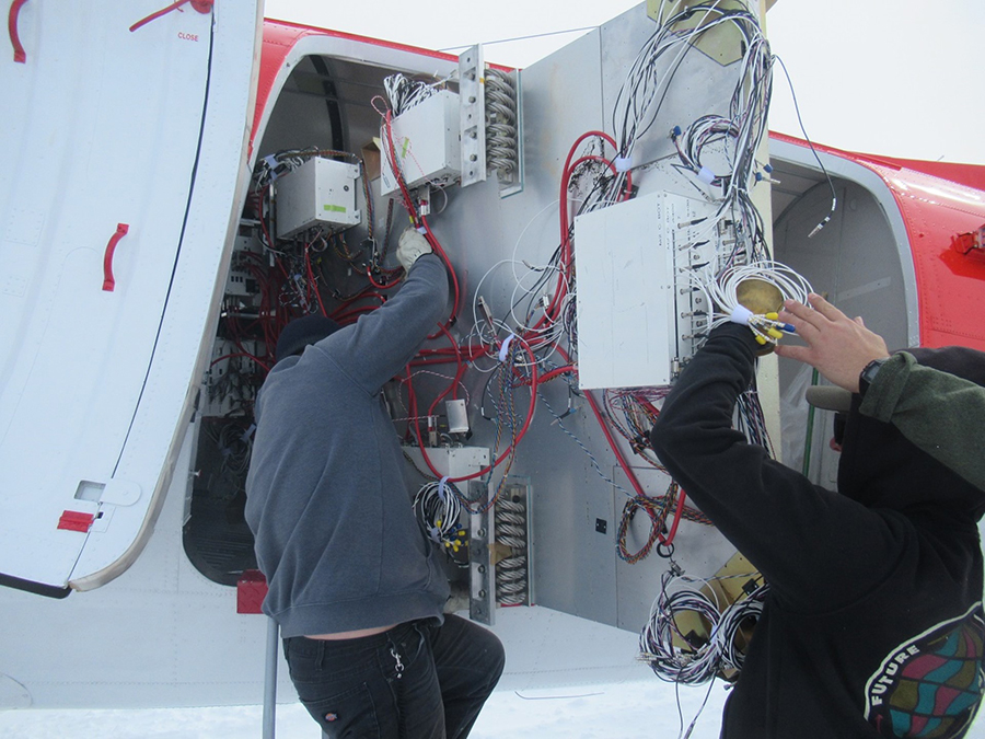 Two of the Basler crewmembers lift parts of the disassembled detectors into the plane. 