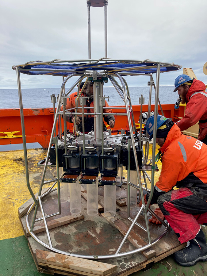 (Left to right) Rich Thompson, Colin Brayton and Alex Brett work to set up the Megacore sampler before it's dropped over the side of the ship to collect samples from the seafloor.
