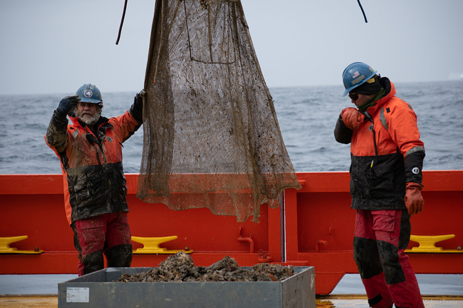 Rich Thompson (left) and Colin Brayton recover and unload samples from a Blake trawl that collected samples from the seafloor. 