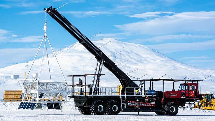 The SuperTIGER-II payload is suspended from a crane during a 'hang test' at the Long Duration Balloon Facility, with Mount Erebus in the background.