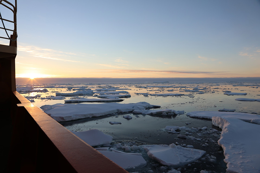 The sun hangs low over the horizon as the research vessel Nathaniel B. Palmer approaches the Thwaites Glacier through icy waters. 