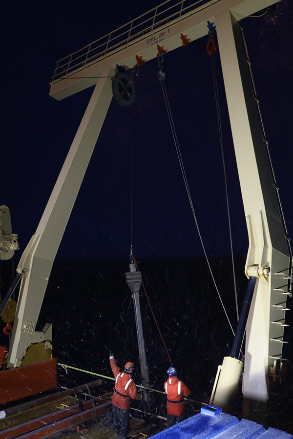 Marine technicians prepare to lower a Kasten corer over the side of the research vessel Nathaniel B. Palmer to collect a column of sediment from the ocean floor. 