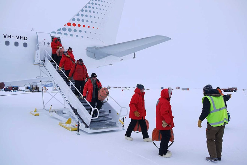 New arrivals to McMurdo deplane at Pegasus Airfield and are directed to a shuttle to take them to the station