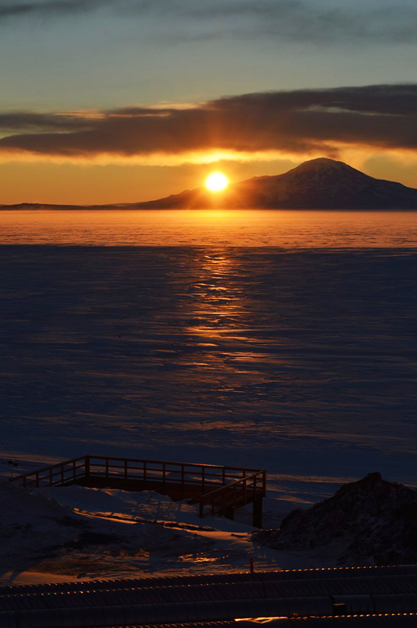 The Sun dips below Mount Discovery in the Transantarctic Mountains across the sea ice from McMurdo Station