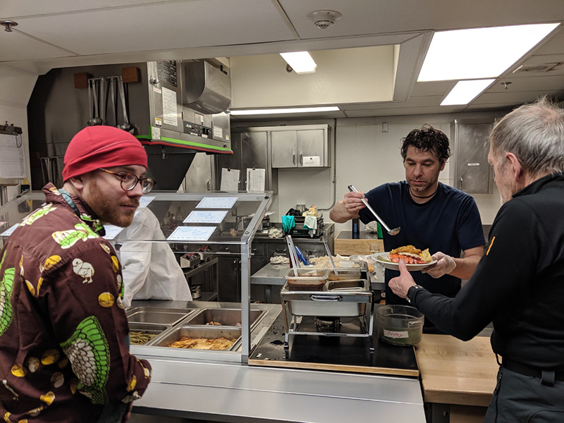 Station residents volunteer in the galley to help prepare the station's big Midwinter dinner