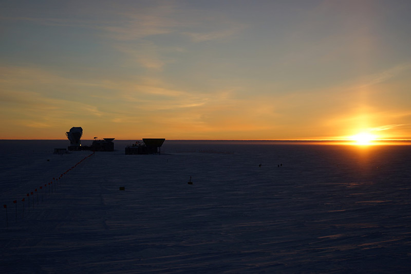 The sun dips below the horizon behind the telescopes of the Dark Sector