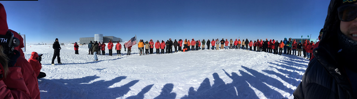 Station members line up to pass the U.S. flag to the new pole marker position