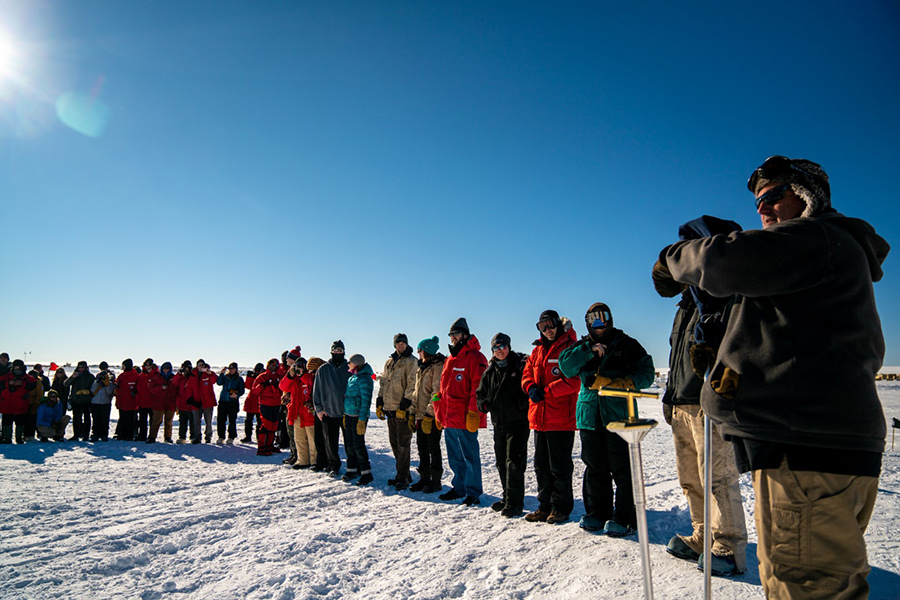 Station residents pass the newly unveiled Geographic South Pole marker to its correct location