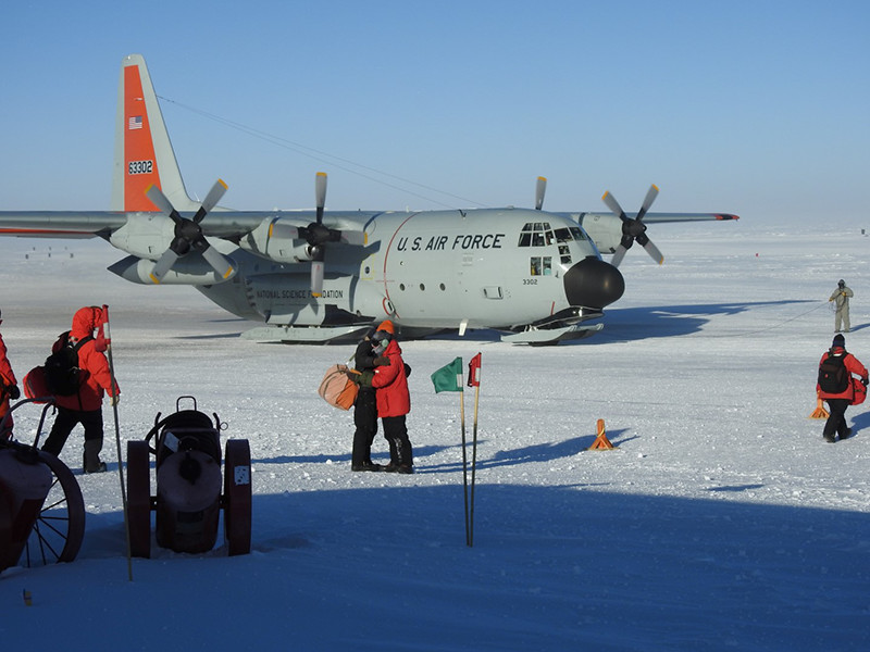 Before one departs on the last flight for the nine months of winter, two people embrace in front of an LC-130