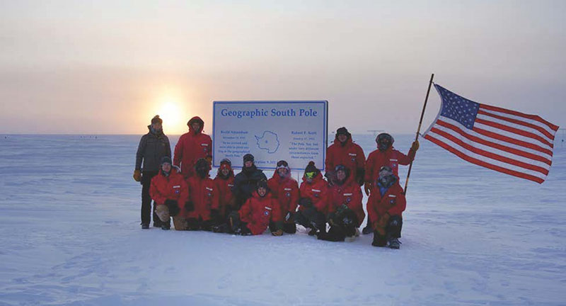Members of the station's winter team gather around the geographic South Pole