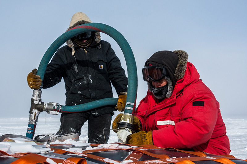 South Pole fuels foreman Jarred (Red) Taylor (left) and Tim Mullen hook a hose up to a full fuel bladder to start unloading it.