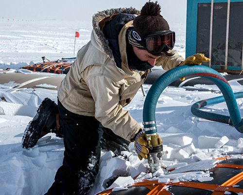Ben Eberhardt hooks a hose up to a fuel bladder. Though not technically a member of the fuels department, Eberhardt will be staying the winter as a technician for IceCube, and will be helping out with other tasks when there are less than 50 people on station.