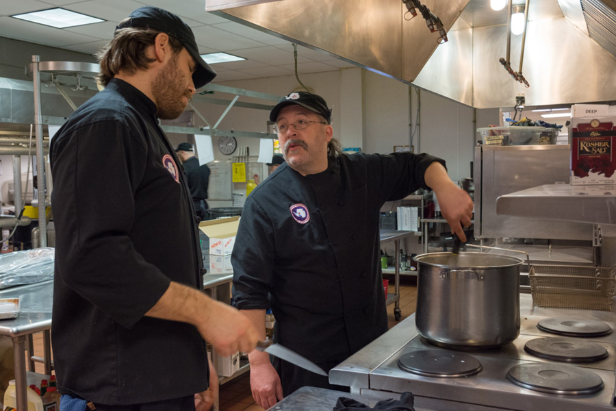 While preparing dinner, Marc Yonkovich (left) and Jonathan Hounsell talk about what’s on the menu for the day