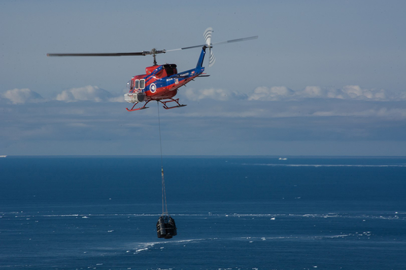 A Bell 212 carries drums of liquid away from Cape Crozier