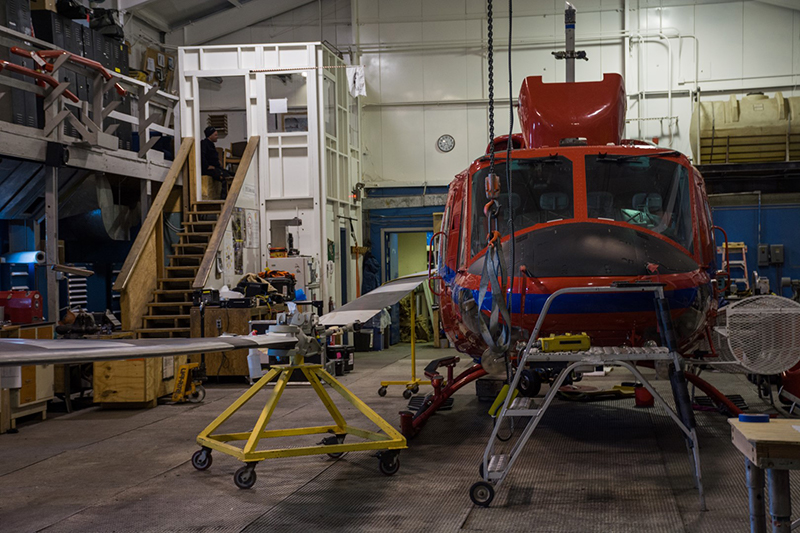 A Bell 212 helicopter undergoes maintenance in McMurdo Station's helicopter hangar