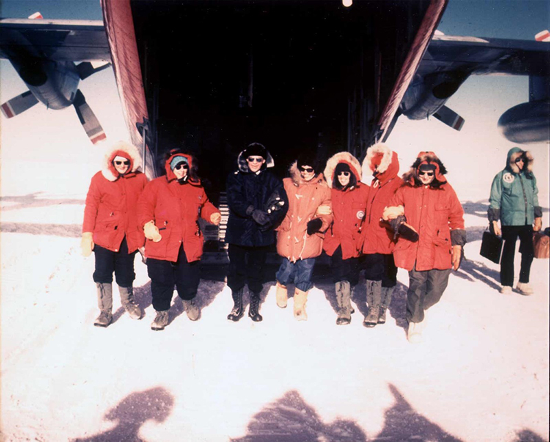 Before setting out for their fieldwork sites in the Dry Valleys, the research team made history as the first women to set foot at the South Pole on November 12, 1969. Though the trip was not required for their research, it showed to the world that women were as capable and proficient as men. The team was joined by Pam Young, a New Zealand biologist, and Jean Pearson, a reporter for the Detroit Free Press, as well as Rear Admiral Kelly Welch, commander of Naval Support Force Antarctica at the time. To make sure that no one of them were the first to walk off the plane, the team locked arms and stepped off the plane as one. (Left to right) Terry Tickhill, Lois Jones, Kelly Welch, Pam Young, Eileen McSaveney, Kay Lindsay, and Jean Pearson.
