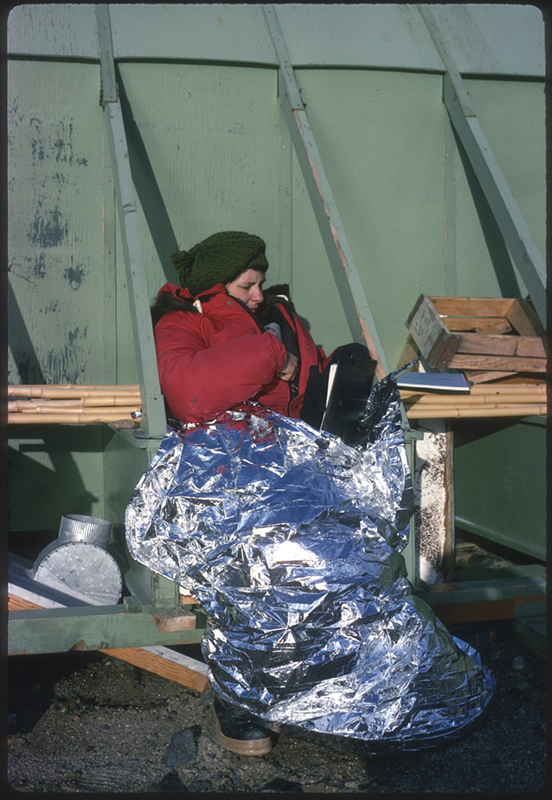 Jones sits outside, wrapped in a Mylar blanket for warmth at the Lake Bonney hut in the Taylor Valley. The hut's furnace didn't work when they first arrived, making for a cold start of their stay.