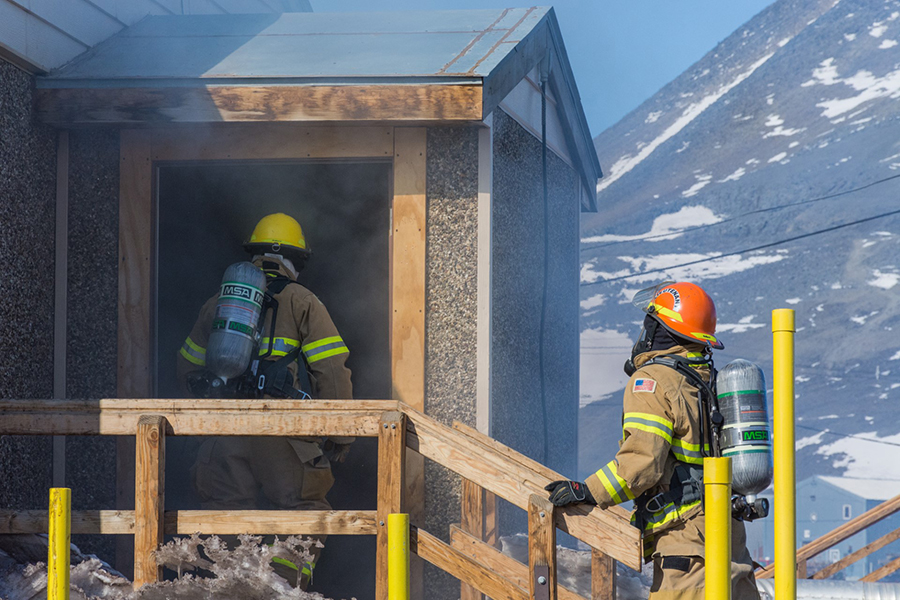 During a practice drill, complete with simulated smoke, two firefighters keep their skills sharp by rehearsing rescuing people from a building. 