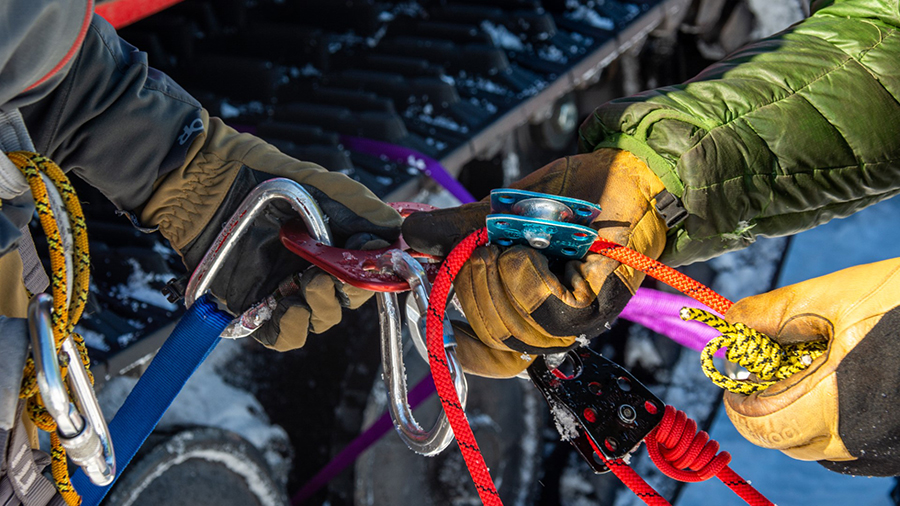 At the crevasse simulator, Mitch Beres (left) helps Federico Piola make sense of the complicated tangle of ropes, knots and climbing equipment.