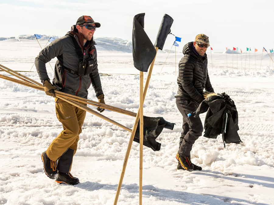 Mitch Beres (left) and Philippe Wheelock carry black flags to a crack in the ice. Black flags mean 'danger, do not approach' so that people stay away from potential hazards.