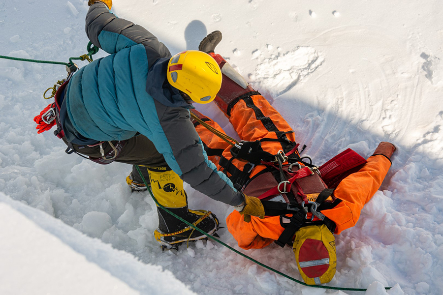 At the bottom of the crevasse simulator, Christina Bovinette attaches a rescue rope to a mock victim. 