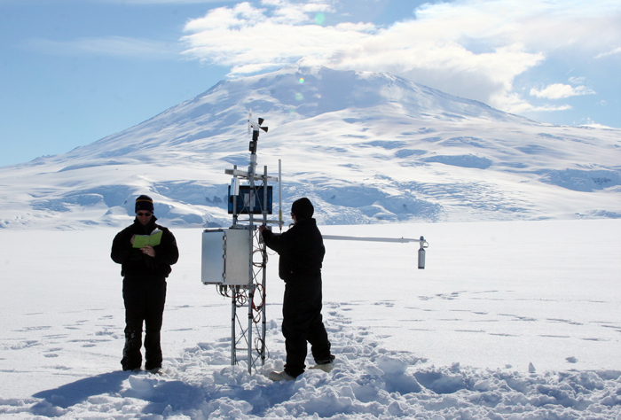 Scientists install instrument on automatic weather station.