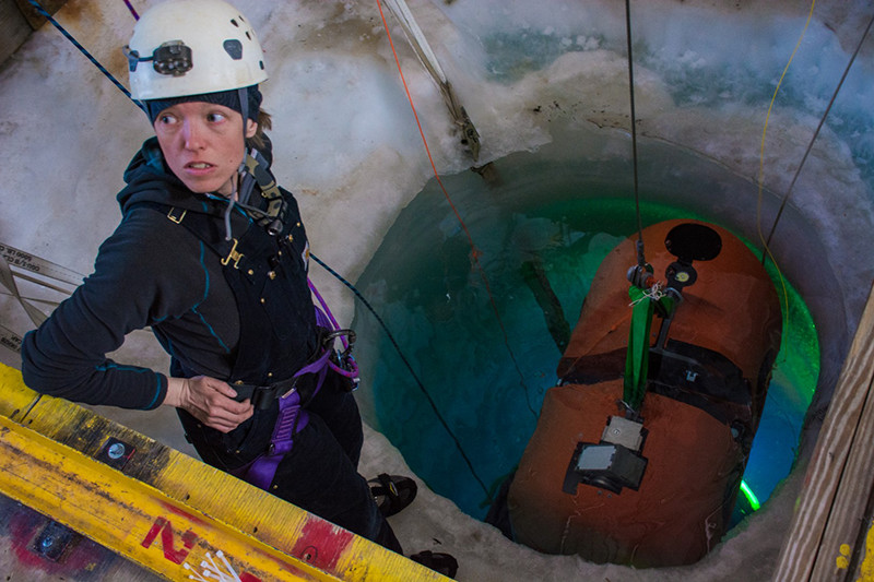 Vickie Siegel looks up from the hole drilled in the sea ice as ARTEMIS is lowered into the water below